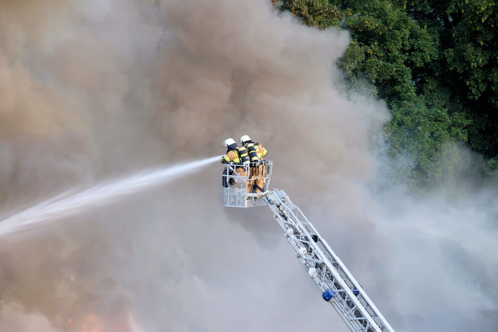 Dos bomberos tratando de apagar el fuego en el bosque rodeado de humo